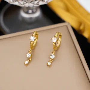 Primer plano de pendientes de acero dorado con circonitas cúbicas colgantes muy brillantes
