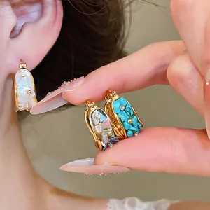 Detalle de pendientes de aro bohemios bañados en oro de 18k con nacre y turquesa