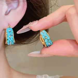 Detalle de primer plano de pendientes de aro de turquesa bañados en oro 18k con cristales