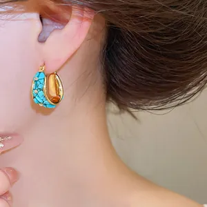 Primer plano de pendientes de aro bañados en oro 18k con piedras turquesas de boho