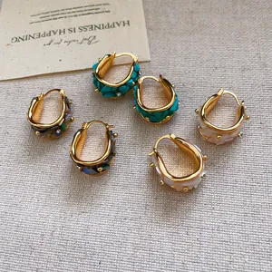 Detalle de pendientes de aro bohemios bañados en oro de 18k con incrustaciones de nácar.