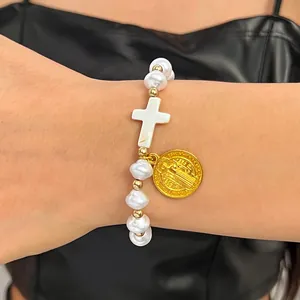 Detailed view of a white baroque pearl bracelet with cross and Saint Benedict medal