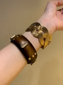 Detail of vintage wooden bangle with gold studs and a braided metal cuff bracelet.