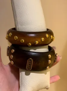 Macro detail of vintage wooden bangles with gold studs and engraved metal plaque.