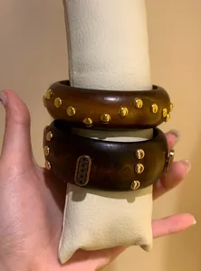 Close-up detail of vintage wooden chunky bangles with gold studs and ornate pattern