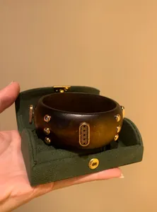 Macro view of vintage wooden wide bracelet with gold studs and geometric carved metal plate