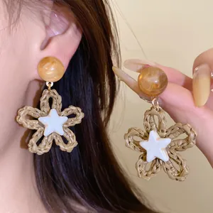 Detailed close-up of woven flower earrings with a star center and amber resin stud