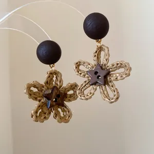 Close-up detail view of woven raffia flower earrings with a star-shaped coconut shell center