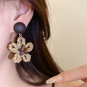Detail of woven paper rope flower and coconut shell star drop earrings for beach style