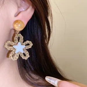 Close-up of woven paper rope flower earrings with star detail for beach vacation style