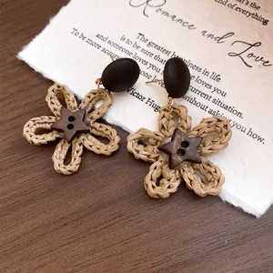 Close-up of boho woven flower earrings with star coconut shell and wood details