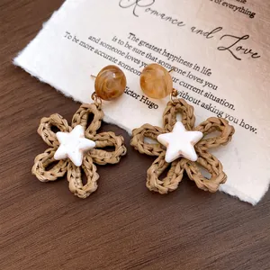 Close-up detail of beach-style woven flower earrings with white star accents on vintage paper