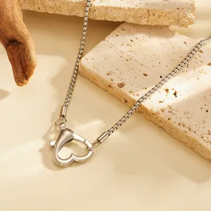 Close-up view of heart-shaped lobster clasp pendant on a silver box chain necklace.