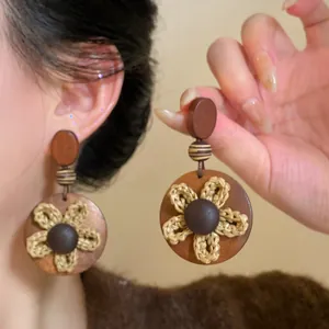 Detailweergave van vintage bruine houten oorbellen met een handgebreid bloemontwerp