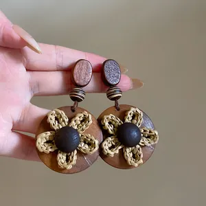 Gedetailleerde macro-opname van vintage bruine houten oorbellen met gevlochten strobloemen
