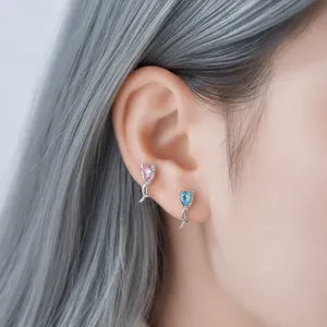 Zilverkleurige oorknopjes met druppelvormige zirkonia in roze en blauw op het oor van model