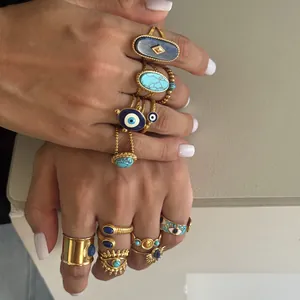 Primer plano de anillos boho apilados con piedras turquesas, lapislázuli y amuleto de ojo turco.