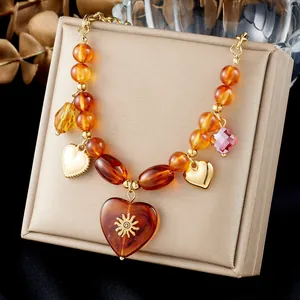 Detailed view of a vintage amber resin heart necklace with gold sun emblem on a box