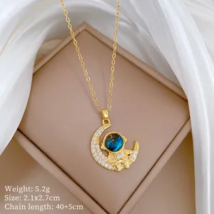 Close-up of gold-plated astronaut moon necklace with blue starry stone and crystals