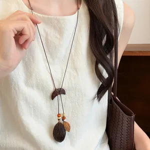 Detail view of a Mori-style wooden necklace with botanical fruit pendants on a model.