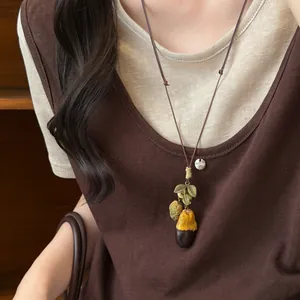 Close-up detail of a vintage Mori style wooden fruit pendant necklace worn by a female model