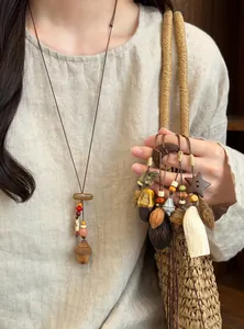 Close-up of handmade Mori style wooden botanical fruit pendant necklaces with ethnic beads.