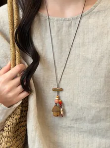 Close-up detail of forest-style wooden acorn pendant necklace worn on linen clothing