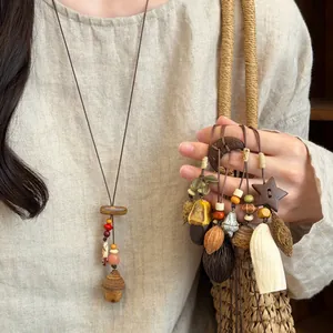 Detail view of handmade Mori-style wooden and plant fruit pendant necklaces on linen