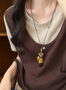 Close-up view of a Mori-style wooden acorn pendant necklace worn on model featuring earthy tones