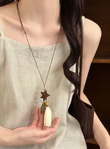 Close-up of a Mori-style necklace with wooden star and white plant seed pendant on a model