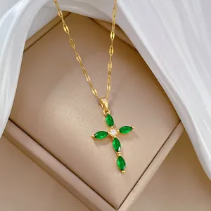 Detailed close-up view of an elegant gold cross necklace featuring emerald-green marquise stones