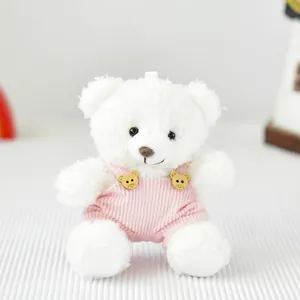 Dettaglio di un orsetto di peluche bianco con salopette di velluto a coste rosa.