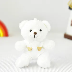 Primo piano di un morbido orsetto di peluche bianco con una graziosa salopette in velluto