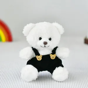 Dettaglio di un piccolo orsetto di peluche bianco con una simpatica salopette nera a bottoni
