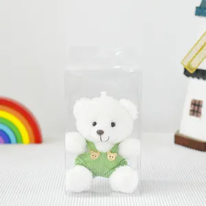 Orsetto di peluche bianco con salopette verde in una scatola regalo in plastica