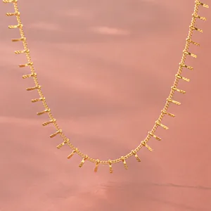 Close-up of gold stainless steel necklace with delicate vertical bar tassels and fringe details.