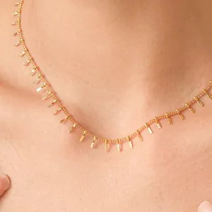 Close-up detail of a minimalist gold stainless steel tassel necklace on a model's neck