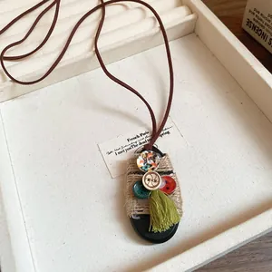 Primo piano di un ciondolo vintage etnico con corda di canapa e nappa verde oliva.
