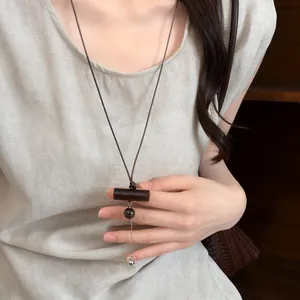 Primo piano di una collana etnica con ciondolo in legno indossata da una modella
