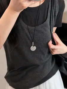Primo piano di una collana etnica vintage con ciondolo geometrico argento su cordino nero.