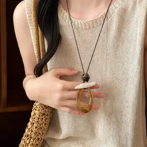 Primo piano di una collana vintage con ciondolo geometrico in resina nei toni caldi dell'ambra