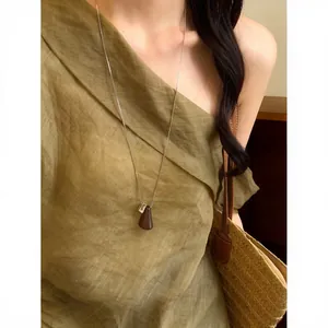 Elegante primo piano di una collana vintage con ciondolo geometrico in legno indossata