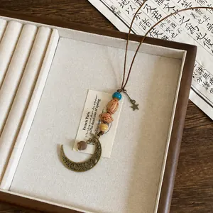 Dettaglio di collana etnica vintage con perle di legno e pendente a mezzaluna in ottone