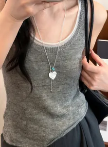 Model met een stijlvolle zilveren hartjesketting met een elegante blauwe harskraal