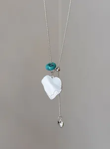 Detailopname van een zilveren hars hart hanger ketting met een turquoise accent.
