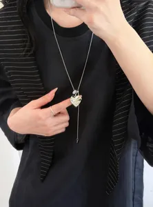 Detailopname van een stijlvolle zilveren ketting met hartjeshanger gedragen door model