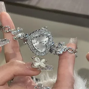 Close-up view of elegant heart-shaped rhinestone watch with dainty flower charm bracelet