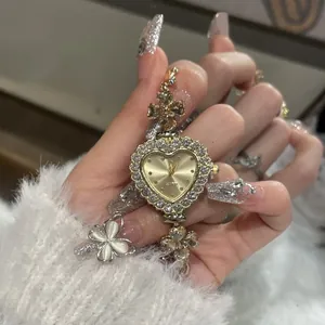 Detailed close-up of a heart-shaped watch with rhinestone flower bracelet links on hand.