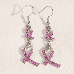 Detail der silbernen Ohrringe mit pinkfarbenen, strassbesetzten Schleifen-Anhängern.