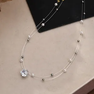 Exquisites Detail einer zweilagigen Halskette mit weißen Perlen und Kristallanhänger